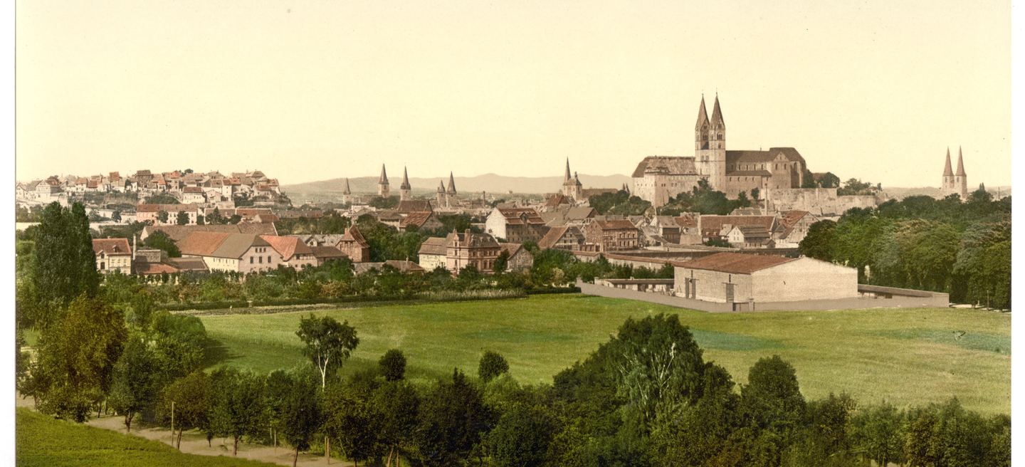 Historische Farbfotografie von Quedlinburg um 1900: über der Altstadt die Stiftskirche St. Servatius auf dem Schlossberg, davor Wiesen und Obstbäume.