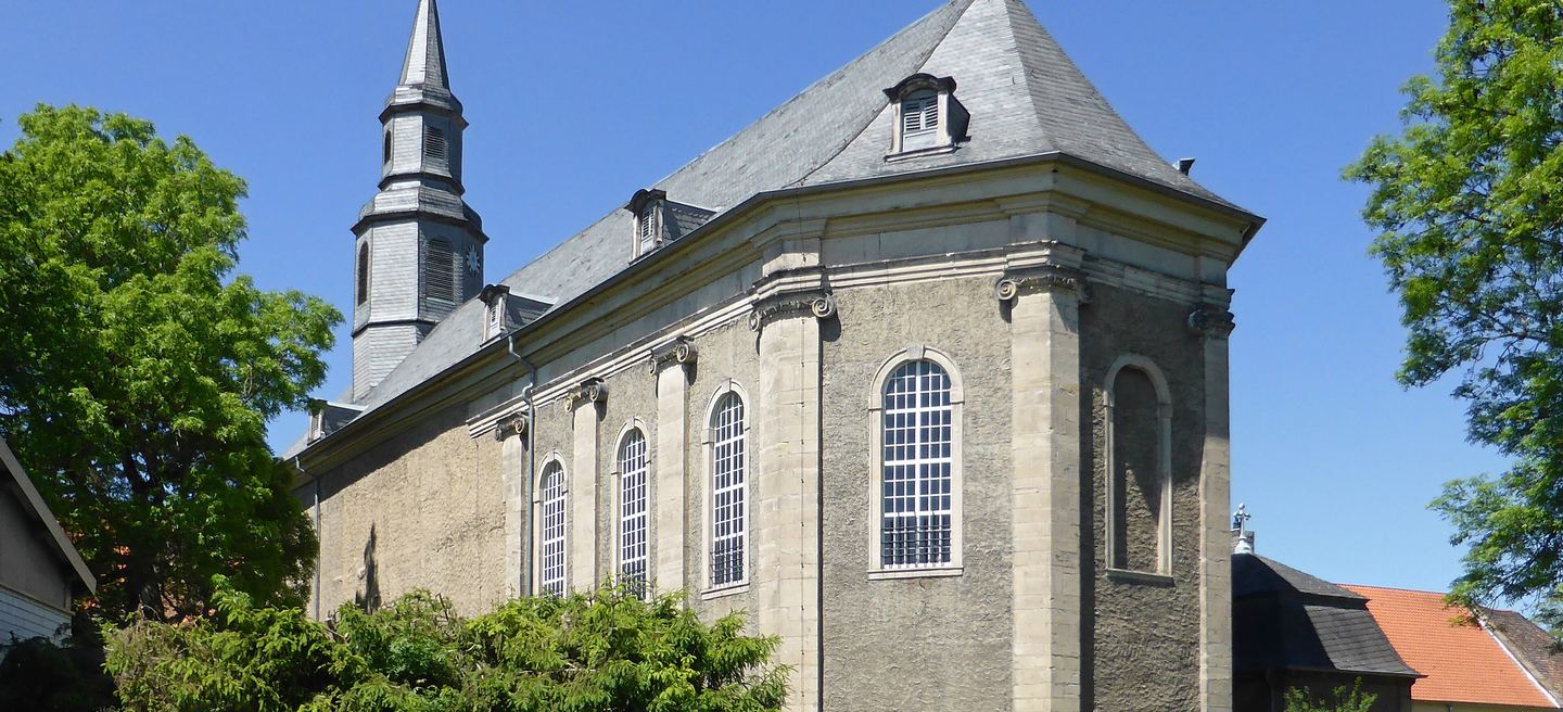 Klosterkirche Marienstuhl in Egeln: grauer Bruchsteinbau mit Schieferdach, hohen Rundbogenfenstern und schlankem Dachreiter, davor Bäume und Sträucher.
