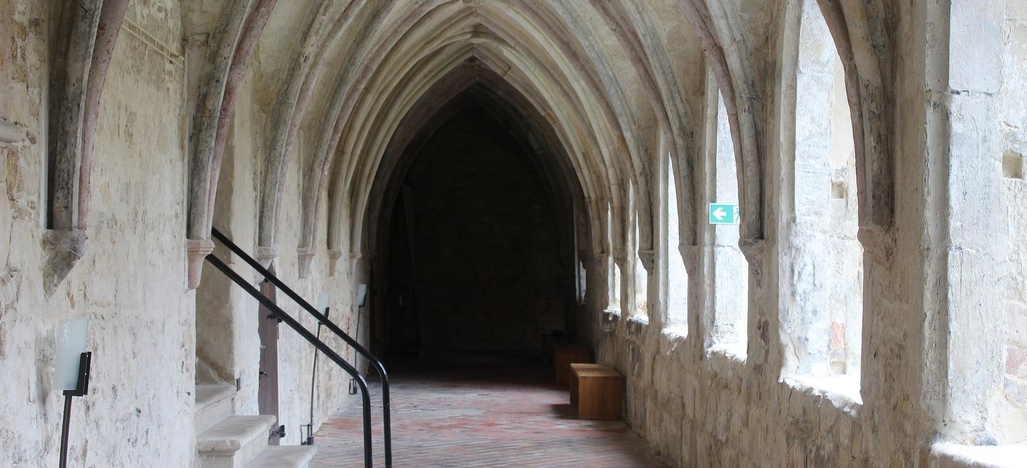 Kreuzgang des Klosters Michaelstein bei Blankenburg: spitzbogiges Gewölbe, schlanke Säulen und helle Wände über einem Ziegelboden.